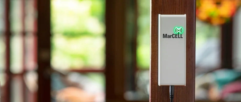 MarCELL cellular monitor installed indoors on a wooden pillar with green LED indicator light.